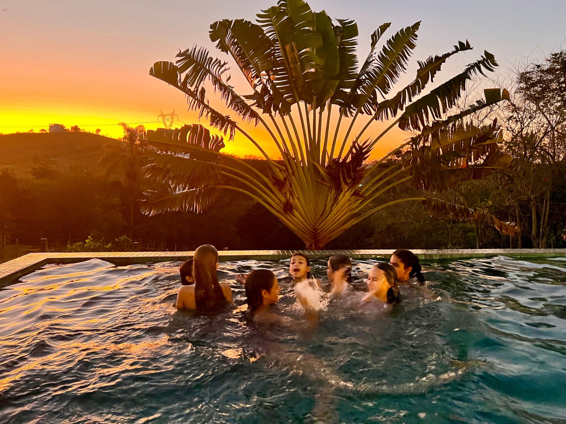 Piscina ao pôr do sol com hóspedes
